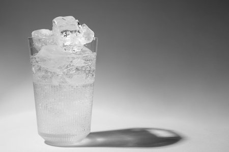 Refreshing water with ice in glass on gray background. Space for textの写真素材