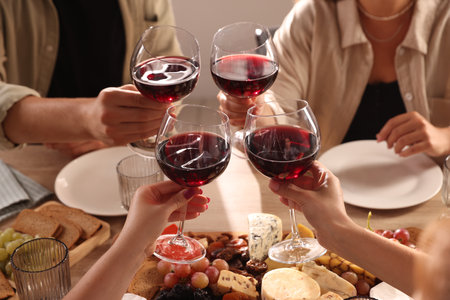 People clinking glasses of red wine at served table, closeupの写真素材