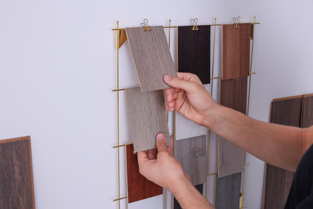 Man with different samples of wooden flooring indoors, closeup