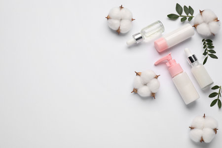 Different cosmetic products, cotton flowers and leaves on white background, flat lay. Space for textの写真素材
