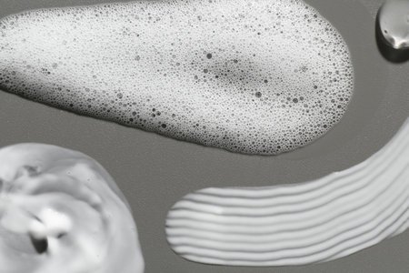 Smears of different cosmetic products on gray background, closeup
