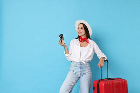 Happy young woman with suitcase and vintage camera on light blue background, space for textの写真素材