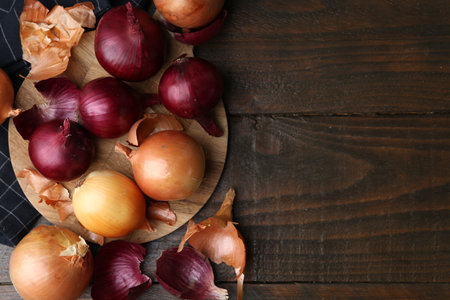 Fresh onions with peels on wooden table, flat lay. Space for textの写真素材