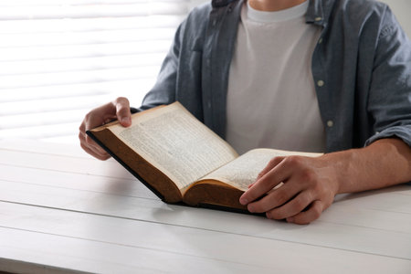 Man with Bible at white wooden table, closeupの写真素材