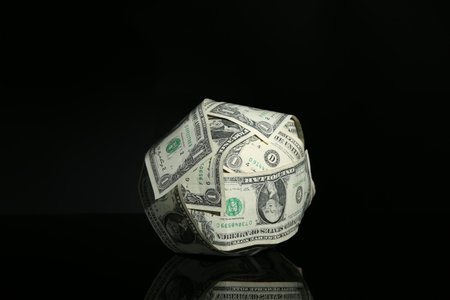 Ball made of dollars on black mirror surfaceの写真素材