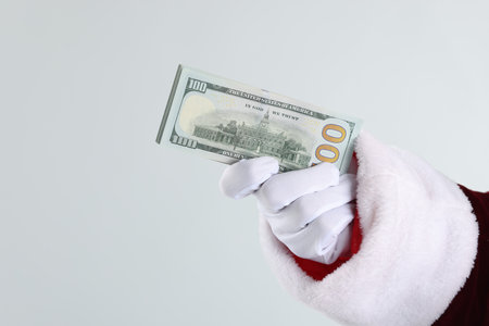 Santa Claus holding dollar banknotes on gray background, closeup. Space for textの写真素材