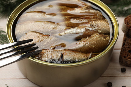 Tasty sprats in tin can and fork on wooden table, closeupの写真素材