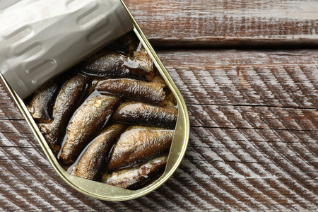 Tasty sprats in tin can on wooden table, top view. Space for textの写真素材