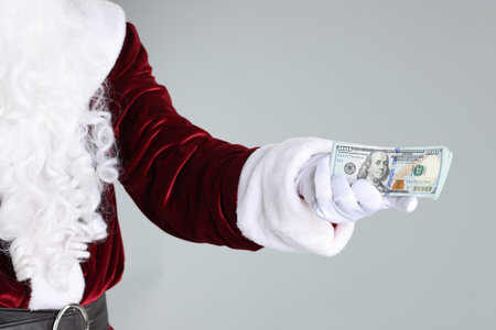 Santa Claus holding dollar banknotes on gray background, closeupの写真素材
