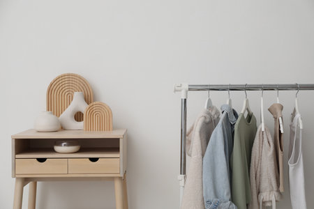 Rack with clothes and standing desk near white wallの写真素材