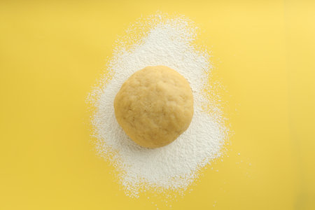 Cooking homemade pie. Raw dough and flour on yellow background, top viewの写真素材