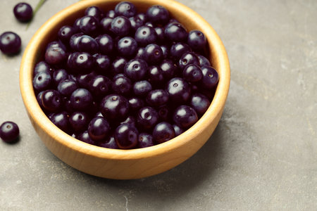 Ripe acai berries in bowl on gray textured table, closeupの写真素材