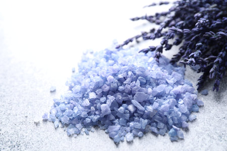 Natural sea salt and lavender flowers on gray table, closeup