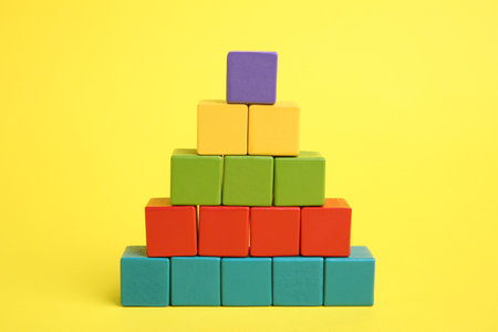 Pyramid of colorful cubes on yellow background