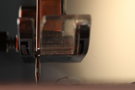 Sewing machine on light background, macro view. Space for text