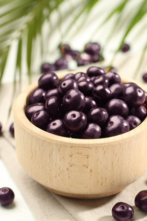 Ripe acai berries in bowl on light table, closeupの写真素材