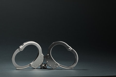 Metal chain handcuffs on gray background, closeup. Space for text