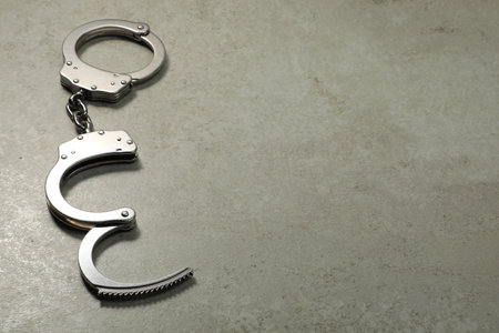 Classic chain handcuffs on gray table, space for textの写真素材