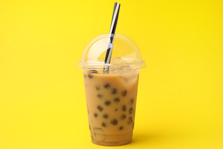 Tasty milk bubble tea in plastic cups on yellow backgroundの写真素材