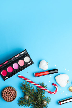 Flat lay composition with makeup products and Christmas decor on light blue background. Space for textの写真素材