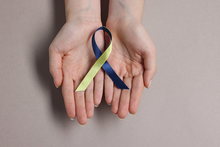 Woman with yellow and blue ribbon on gray background, top view. Down syndrome awarenessの写真素材