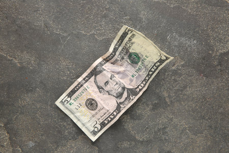 One crumpled dollar banknote on gray table, top view