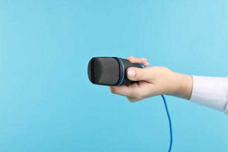Woman with microphone on light blue background, closeupの写真素材