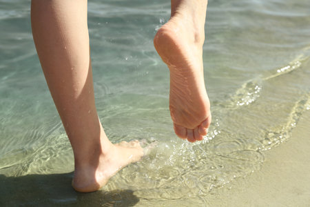 Woman walking barefoot through water on riverbank, closeupの写真素材
