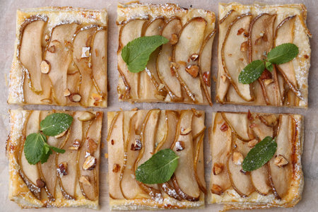 Tasty puff pastry pie with pears and mint on parchment paper, top viewの写真素材