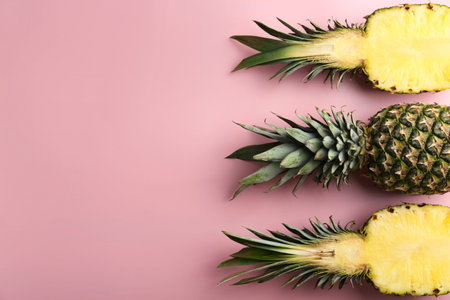 Whole and cut pineapples on pink background, flat lay. Space for textの写真素材