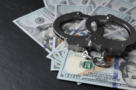 Corruption. Handcuffs and dollar banknotes on black table, closeupの写真素材