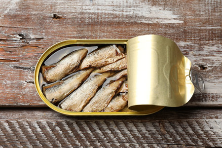 Tasty sprats in tin can on wooden table, top viewの写真素材