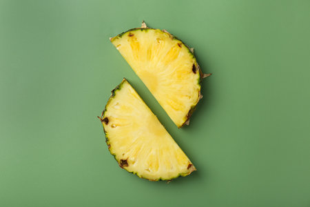 Slices of fresh pineapple on green background, flat layの写真素材