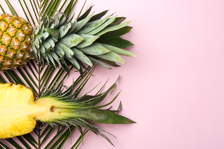 Fresh ripe pineapples and palm leaves on pink background, flat lay. Space for textの写真素材