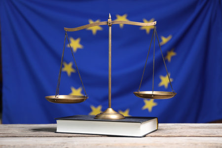 Scales of justice and book on wooden table against European Union flagの写真素材