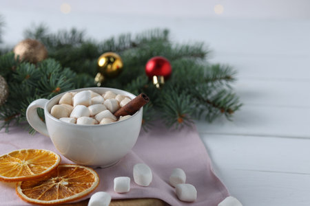 Yummy cocoa with marshmallows in cup, dried orange slices and Christmas wreath on white wooden table. Space for textの写真素材