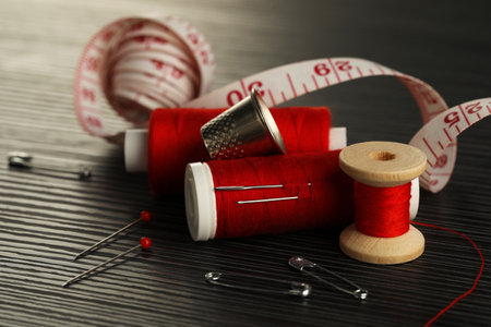 Different sewing tools on wooden table, closeup
