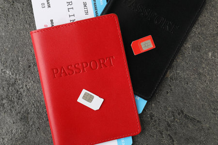 Passports with tickets and SIM cards on gray textured table, flat layの写真素材