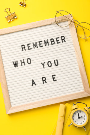 Flat lay composition of letter board with phrase Remember Who You Are on yellow backgroundの写真素材