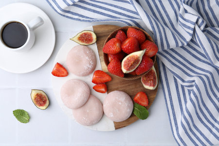 Delicious mochi, strawberries, figs and coffee on white tiled table, top viewの写真素材