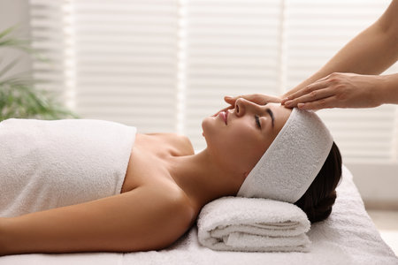 Attractive woman enjoying face massage in spa salonの写真素材
