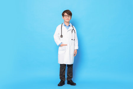 Boy with stethoscope pretending to be doctor on light blue background. Dreaming of future professionの写真素材