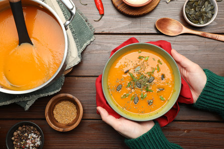 Woman with delicious pumpkin soup at wooden table, top viewの写真素材