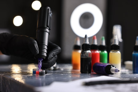 Professional artist working with tattoo machine and inks at sterile table in salon, closeupの写真素材