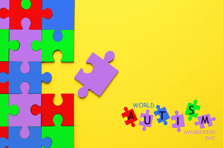 World Autism Awareness Day text and colorful puzzle pieces on yellow background, top viewの写真素材