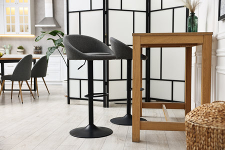 Bar stools and table near folding screen indoors