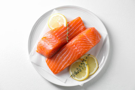 Pieces of fresh salmon with thyme and lemon on white table, top viewの写真素材