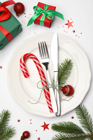 Christmas table setting with plate, cutlery and festive decor on white background, flat layの写真素材