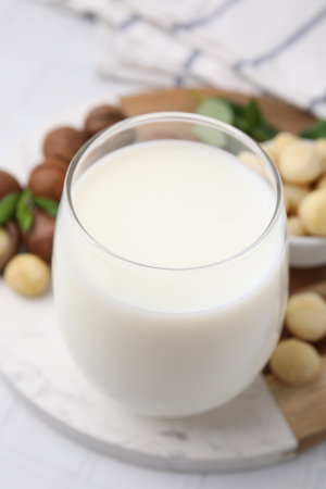 Glass of macadamia milk and nuts on white tiled table, closeupの写真素材