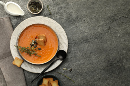 Delicious pumpkin soup with spices served on gray textured table, flat lay. Space for textの写真素材